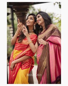 two beautiful women standing next to each other in colorful sari outfits and smiling at the camera