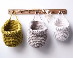 three crocheted baskets hanging on a wall