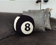 a black and white eight ball pillow sitting on top of a couch next to pillows