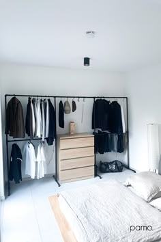 a bedroom with clothes hanging on the wall and an inspire logo above it