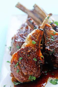 two pieces of meat on a plate covered in sauce and garnished with parsley