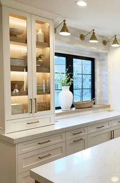 a large kitchen with white cabinets and marble counter tops in front of a black window