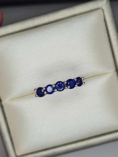 a ring with three blue stones in it sitting on top of a white cloth box