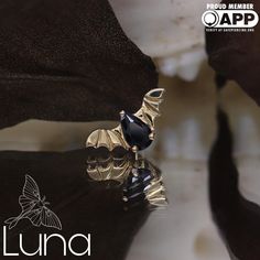 a black and gold ring sitting on top of a white surface with the words lunaa written below it