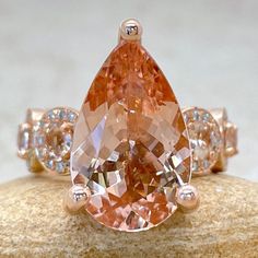 an orange and white diamond ring sitting on top of a piece of stone with diamonds around it