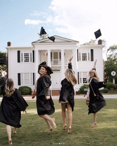 four girls in graduation gowns are throwing their mortars into the air outside of a large white house