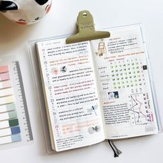 an open planner book sitting on top of a desk next to a calculator