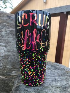 a cup that is sitting on top of a wooden table with confetti sprinkles