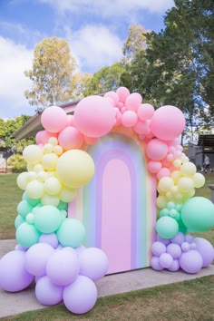 an arch made out of balloons in the shape of a rainbow is on display outside