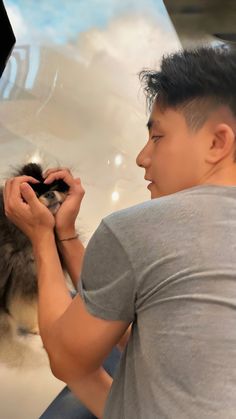 a man holding a small animal in his hands while looking at it's reflection