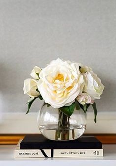 a vase filled with white flowers sitting on top of two books