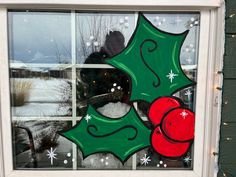 a window decorated with christmas decorations and holly wreaths on the outside, in front of a house