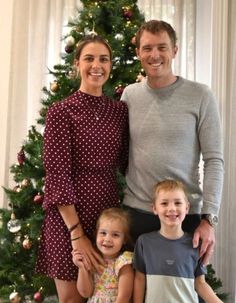 a man and two children standing in front of a christmas tree