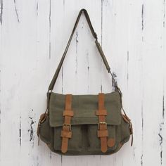 Crafted of sturdy green canvas this roomy messenger bag keeps things organized. Four outer pockets are easily accessible while a zipper pocket is hidden on the inside of the flap. By Karina and Maybee the bag is lined in dark beige cotton and opens to reveal another zipper pocket. Leather trim adds to its appeal and the shoulder strap is adjustable in length. Green Canvas Bag With Pockets, Khaki Satchel With Pockets For School, Green Canvas Bags With Pockets, Green Shoulder Satchel With Pockets, School Satchel With Pockets In Khaki, Canvas Satchel Bag With Multiple Pockets, Khaki Canvas School Satchel, Canvas Satchel In Khaki For School, Green Everyday Satchel With Pockets