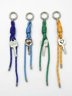 four key chains with keys attached to them, all in different colors and sizes are shown on a white surface