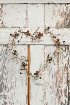 a heart shaped wreath made out of flowers and leaves on an old white painted wooden door