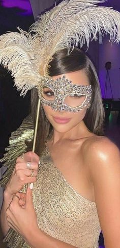 a woman wearing a masquerade and holding an umbrella in her hand at a party