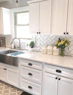 a kitchen with white cabinets, marble counter tops and stainless steel sink in the center