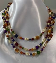 This vintage necklace from an Estate sale is a stunning piece that will add a touch of retro beauty to any outfit. With its layered and beaded design, it features a variety of colorful beads and a gold-colored embellishments and a Spring Ring closure. The necklace measures 22 inches in length and is perfect for a range of occasions, including Mother's Day, Christmas, graduation, anniversary, birthday, confirmation/communion, and Valentine's Day. This necklace is a great choice for anyone who lov Vintage Multicolor Multi-strand Beads, Vintage Multi-strand Beaded Necklaces With Colorful Beads, Vintage Multi-strand Beaded Necklace With Colorful Beads, Vintage Multi-strand Colorful Beaded Necklaces, Vintage Multicolor Necklaces With Colorful Beads, Vintage Multicolor Beaded Necklaces, Vintage Multicolor Faceted Beads Necklace, Gold Double Strand Necklace With Colorful Beads, Multicolor Beaded Chain For Costume Jewelry