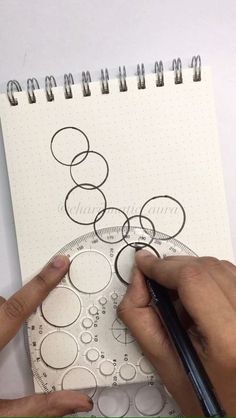 someone is drawing circles on a spiral notebook