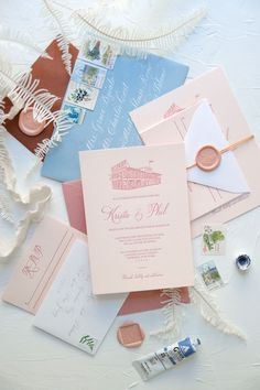 the wedding stationery is laid out on top of each other, including pink and blue