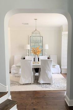 a dining room with white chairs and a chandelier