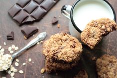 chocolate chip cookies next to a cup of milk and some oats on a table