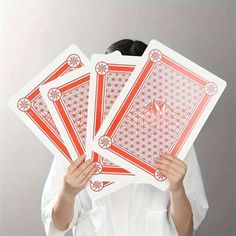 a woman holding four red playing cards in front of her face