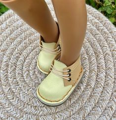 a close up of a doll's legs wearing shoes on a round mat with grass in the background