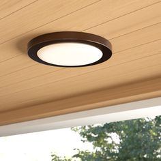 a close up of a ceiling light on a wooden structure with trees in the background