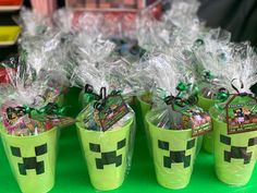 plastic cups filled with candy and wrapped in clear cellophane are sitting on a green table