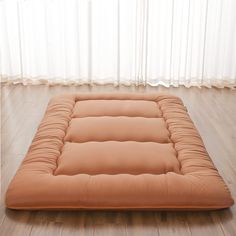 a futon mattress sitting on top of a hard wood floor next to a window