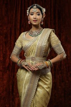 Gold banarasi saree with badla, kasab work, Hyderabadi micro pearls and floral banarasi woven motifs. Paired with half sleeve padded blouse in rose gold kasab, pearl, crystal drop detailing and belt.
Components: 3
Pattern: Woven, Embroidery
Type Of Work: Badla, Kasab, Micro Pearl, Crystal
Neckline: Leaf neck
Sleeve Type: Half sleeves
Fabric: Saree: Banarasi, Blouse: Silk Chanderi, Lining: Taffeta Silk
Color: Gold
Other Details: 
Crystal drops on sleeve hem
Back tassel tie-up
Note: All the jewell Gold Brocade Pre-draped Saree With Zari Weaving, Traditional Blouse With Zari Weaving For Reception, Gold Brocade Pre-draped Saree With Zari Work, Festive Blouse With Zari Weaving For Reception, Festive Reception Blouse With Zari Weaving, Traditional Banarasi Silk Blouse For Reception, Pre-draped Banarasi Silk Saree With Cutdana For Reception, Brocade Pre-draped Saree With Unstitched Blouse, Reception Zari Weaving Blouse Piece For Navratri