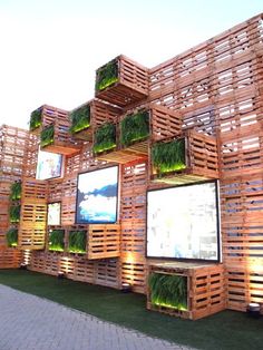 a bunch of wooden pallets stacked on top of each other with plants growing out of them