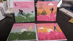 four greeting cards with different designs on them sitting on a desk next to a computer