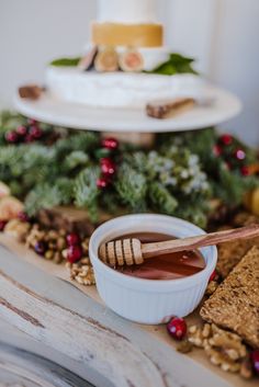 a table topped with crackers and dips next to a cake on top of a wooden platter