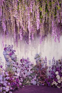 purple and white flowers are hanging from the wall