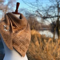 a white mannequin wearing a brown knitted shawl