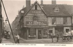 an old black and white photo of a horse drawn carriage in front of a building