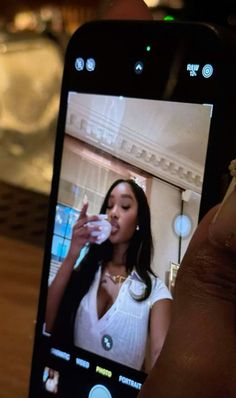 a person holding up a cell phone to take a photo with her face on the screen