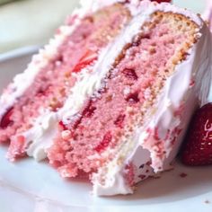 a slice of strawberry cake with white frosting and strawberries on the plate next to it