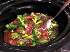 broccoli and meat in a crock pot with a spoon sticking into it