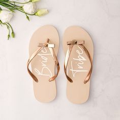 a pair of pink flip flops sitting on top of a white table next to flowers