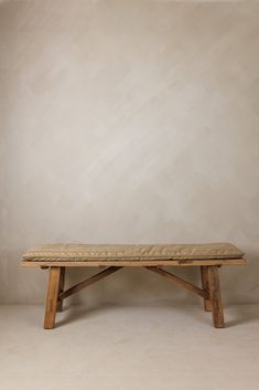 a wooden bench sitting in front of a white wall with no one on it's legs