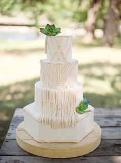 a three tiered white wedding cake with succulents