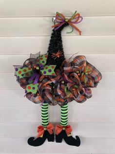 a halloween wreath hanging on the side of a door with green and orange decorations,