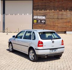 a silver car parked in front of a building with a sign that says vw parking