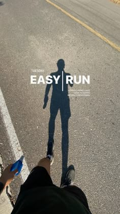 a person standing in the middle of an empty road with their shadow on the ground