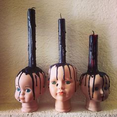 three plastic heads with candles sticking out of them on top of a shelf in front of a wall