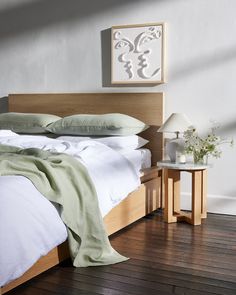 a bed with white sheets and pillows on top of it next to a night stand